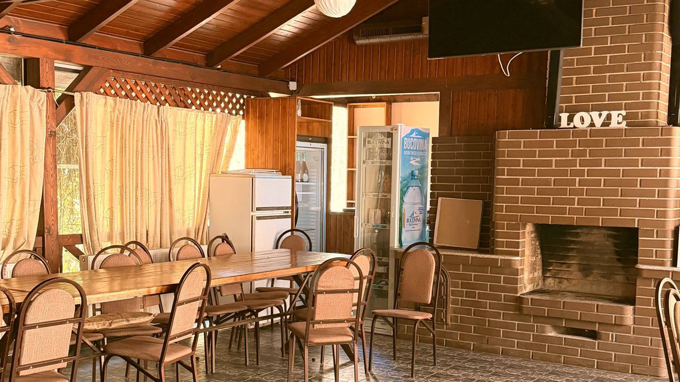 Sala închisă, cu șemineu și mese